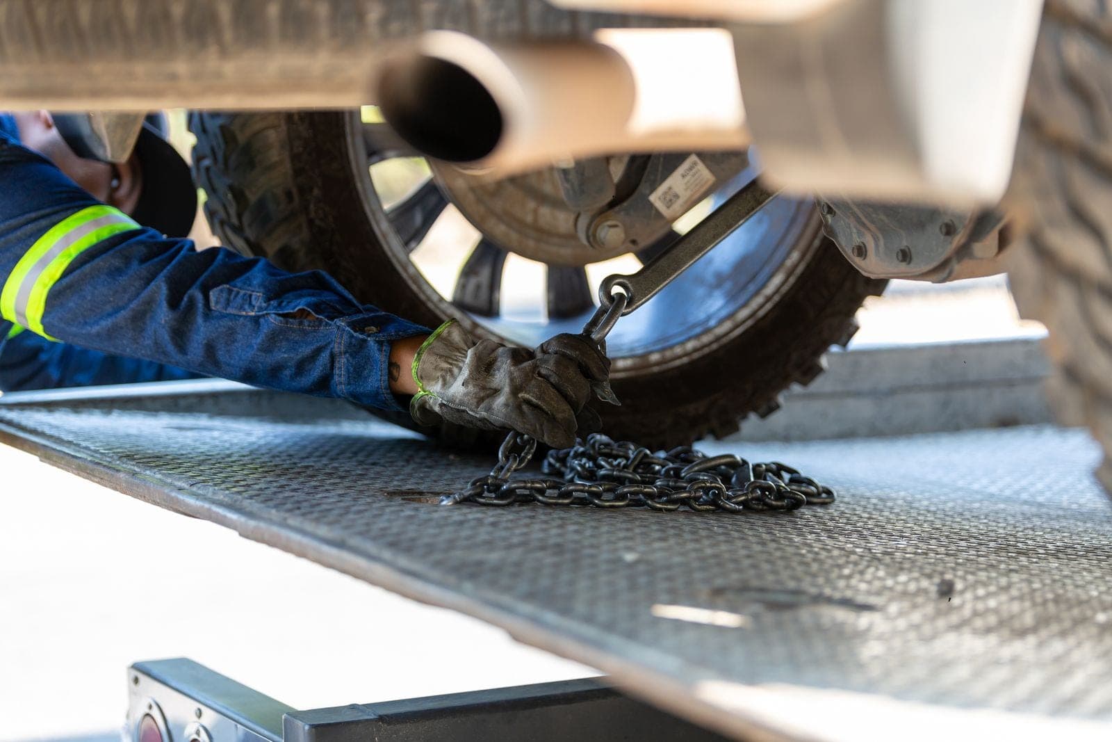 Tow operator securing a vehicle to a carrier deck with a chain