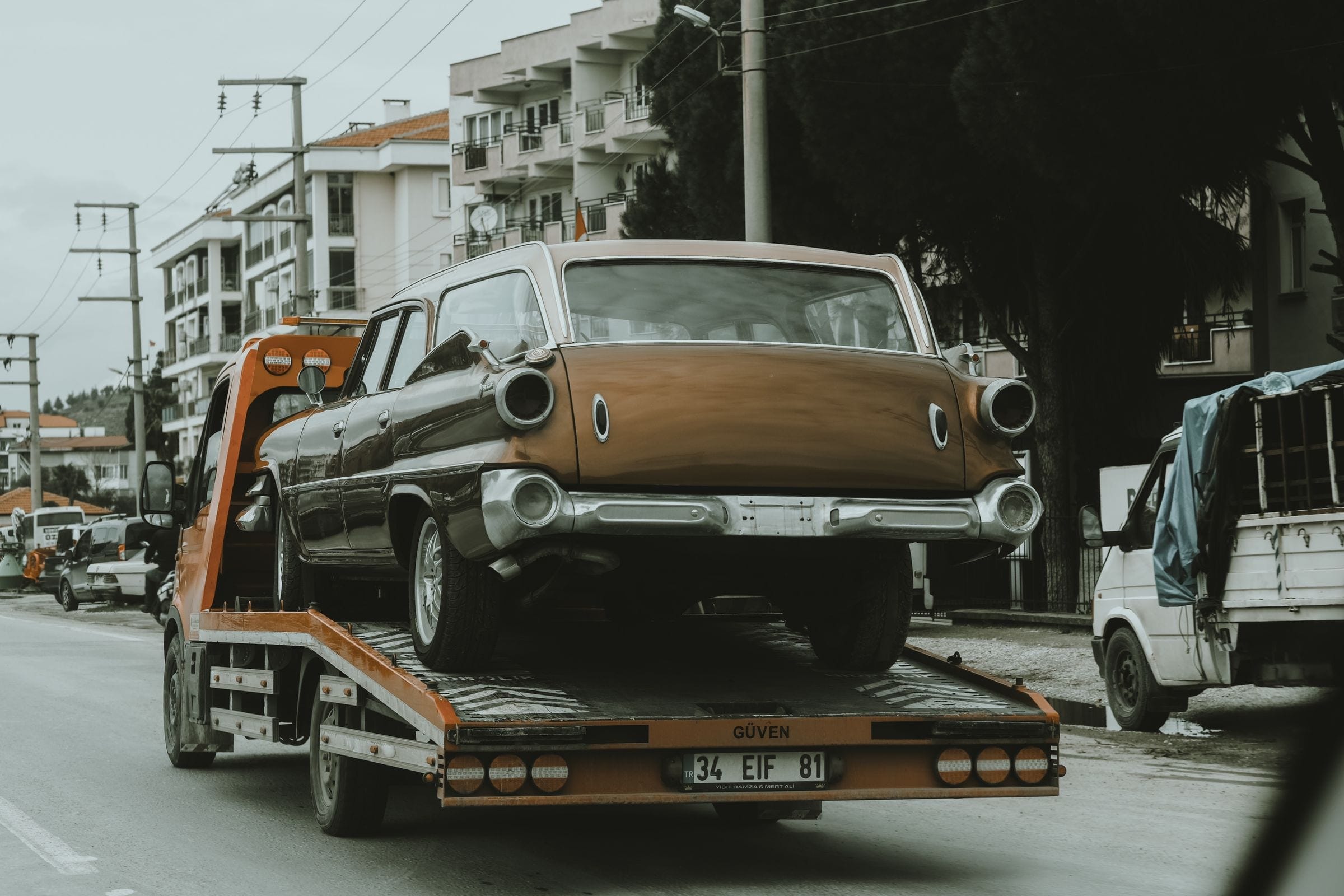 A vintage car loaded on a flatbed tow truck for flatbed towing