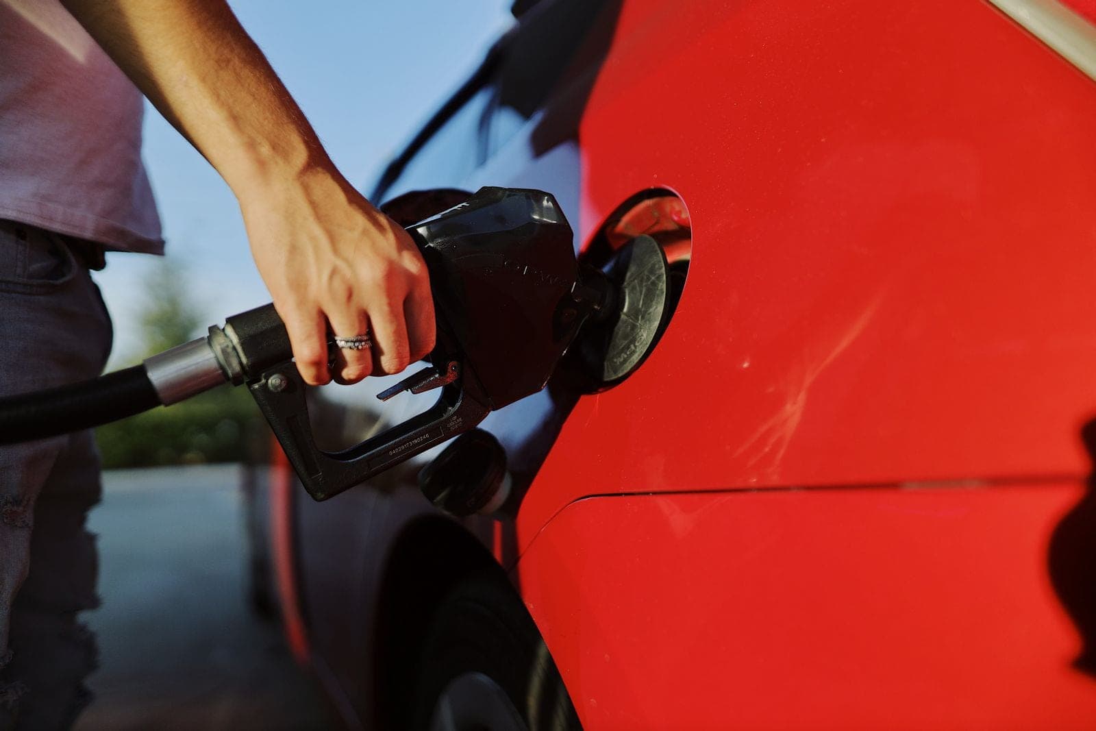 A person refueling a red car
