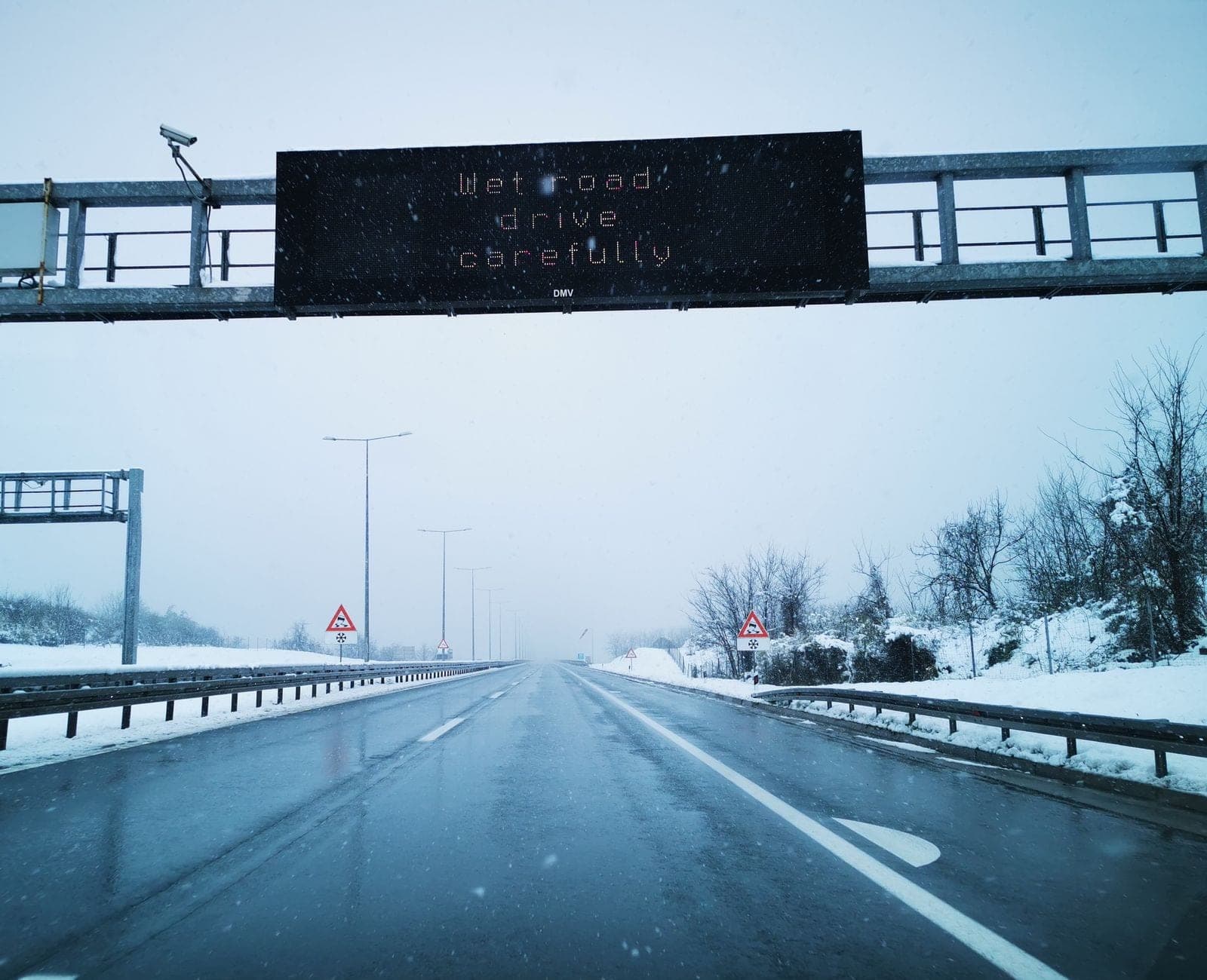 Snowy highway with a caution sign during snowfall