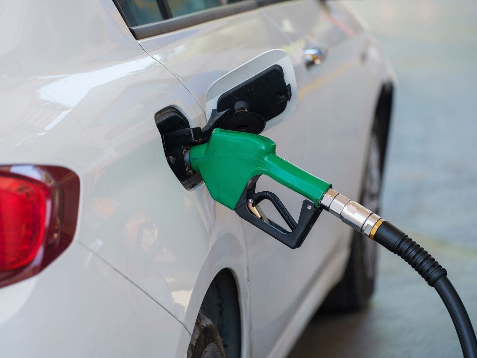 A green nozzle refueling a white car