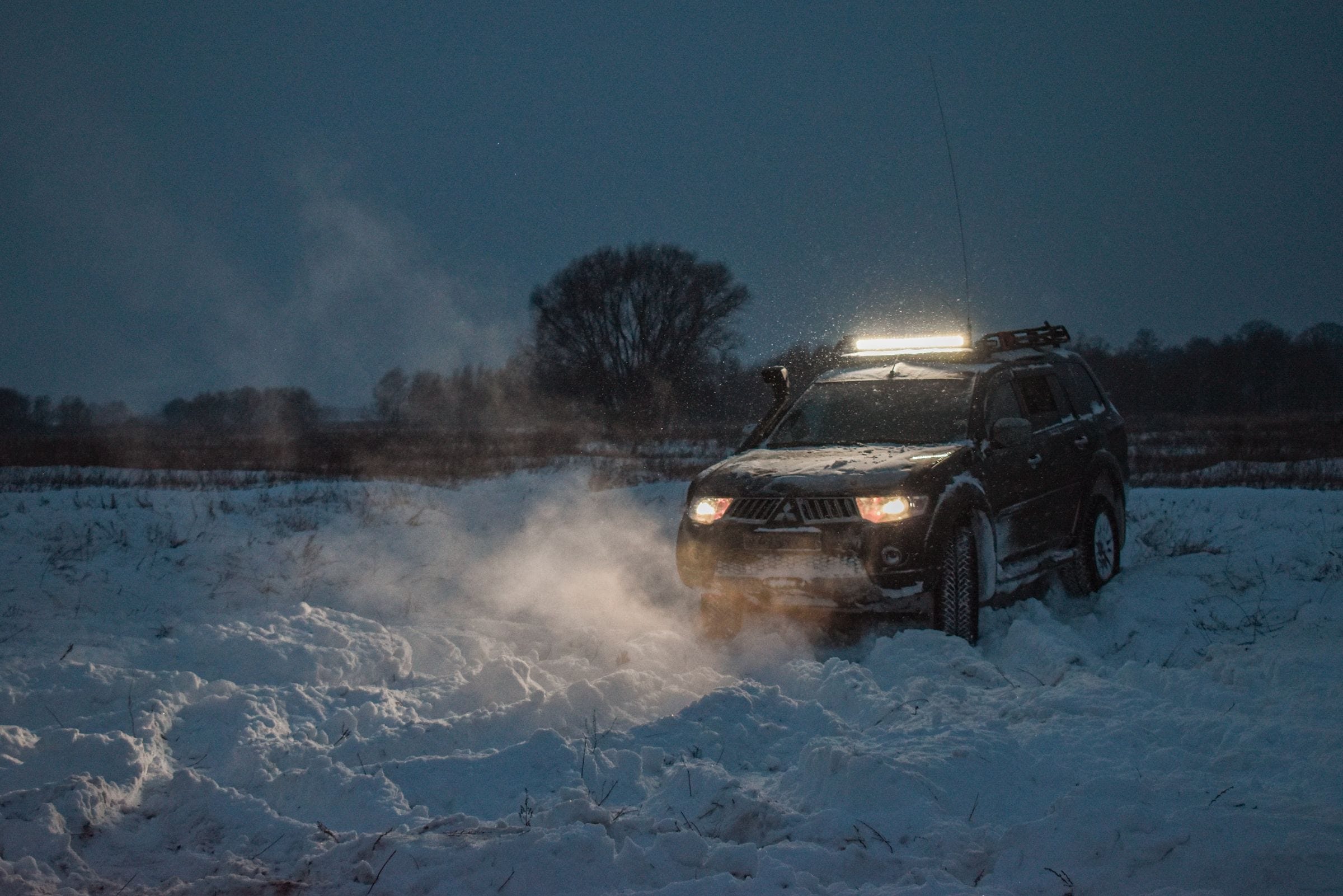 An SUV stuck in deep snow at night that needs a winch out service